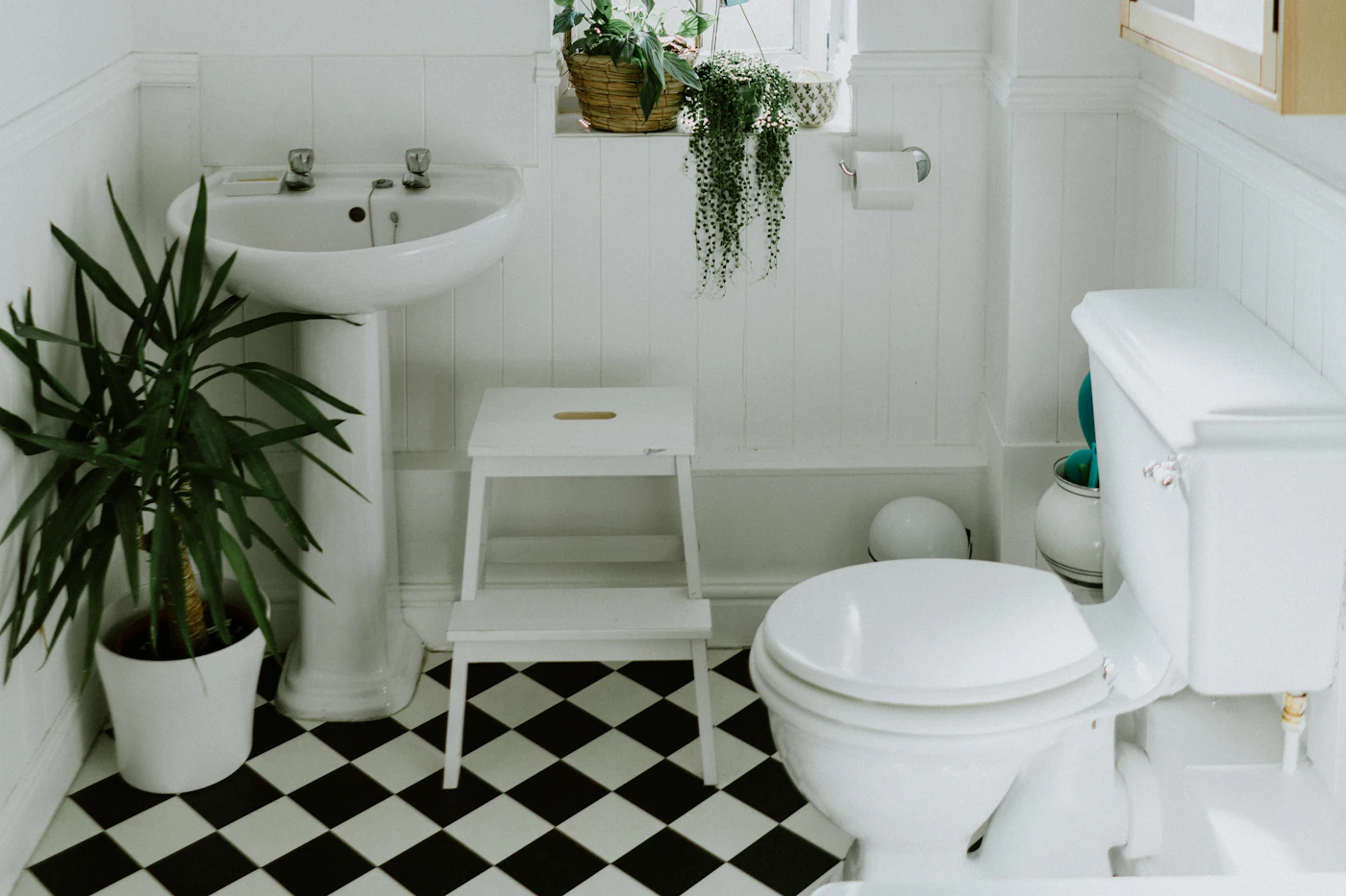 Wit toilet en wastafel in een lichte badkamer met zwart-witte tegelvloer