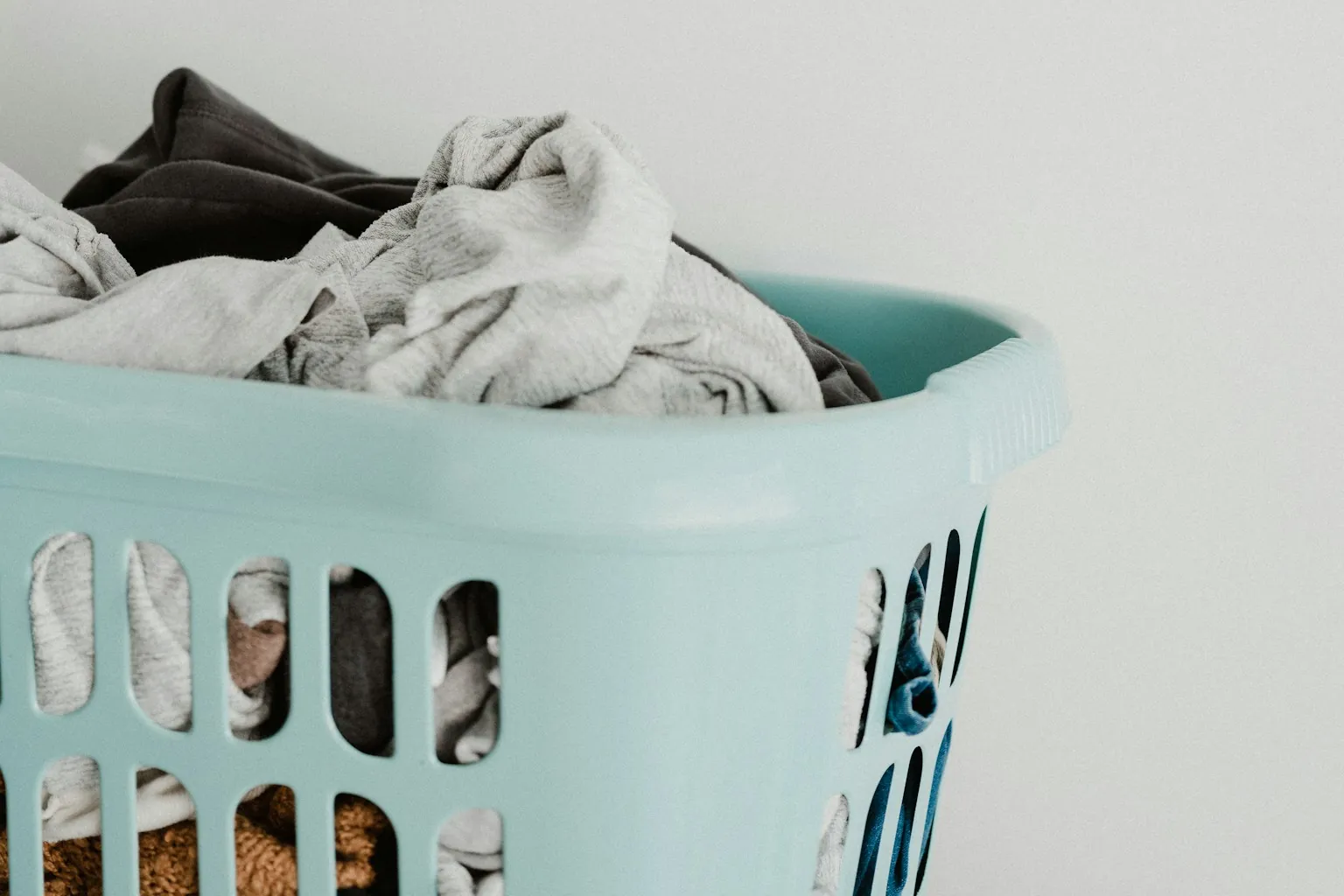 Wasmand met kleding tegen een lichte muur