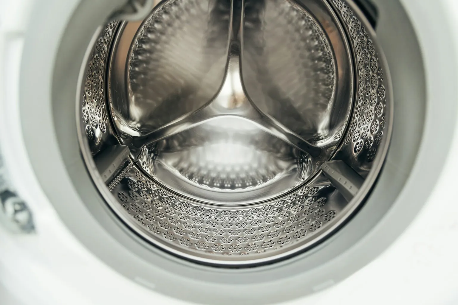 Een lege, schone trommel van een wasmachine door de open deur gezien