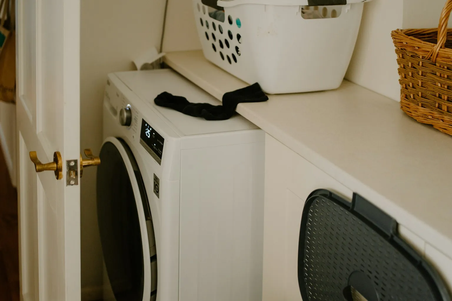 Witte wasmachine onder een werkblad met een wasmand erop